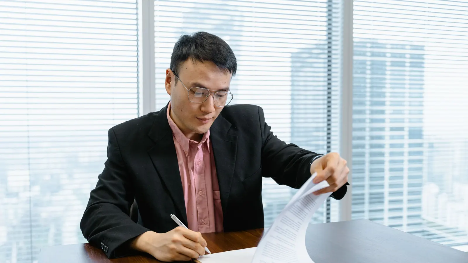 穿西裝的男士在辦公桌前簽署文件